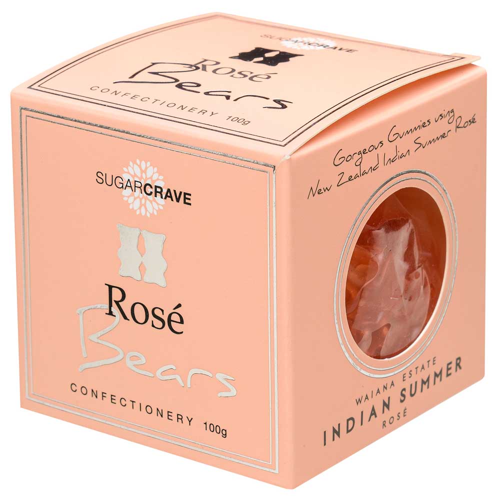 A square peach-colored confectionery box for Sugarcrave Rosé Bears, featuring a circular clear window that reveals two pinkish-orange gummy bears inside. The packaging displays elegant typography and a floral logo on a clean white background.