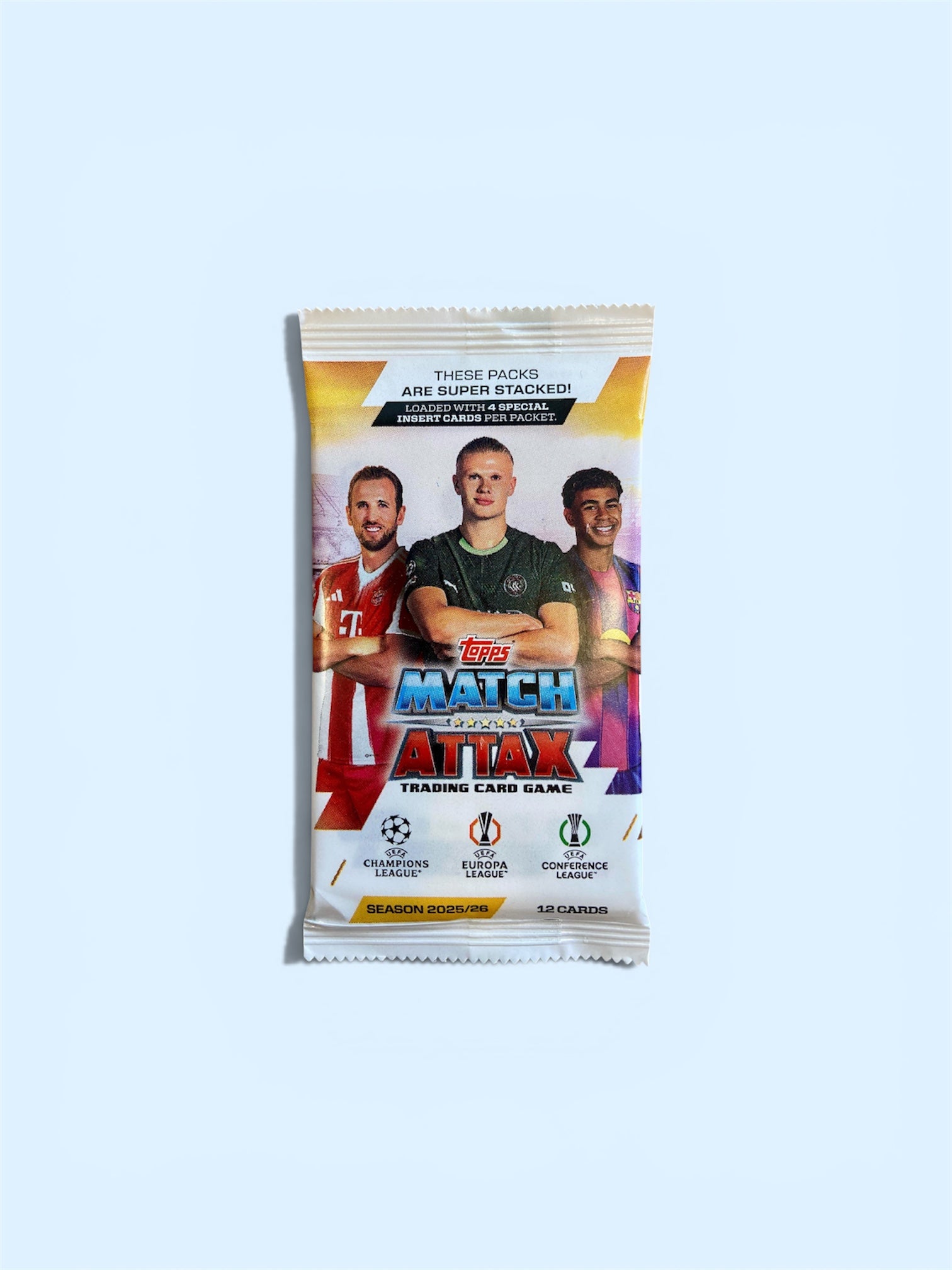 A sealed Topps Match Attax trading card booster pack centered on a pale blue background. The pack features photos of soccer players and prominent Topps branding.
